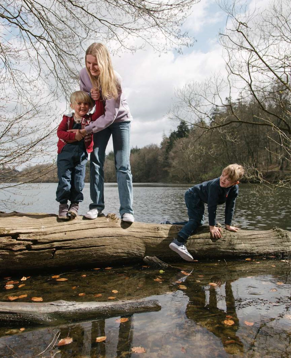 Børn klatrer på træstamme i vandet ved Langesø